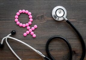 Female diseases concept. Stethoscope near female sign on dark wooden background top view.